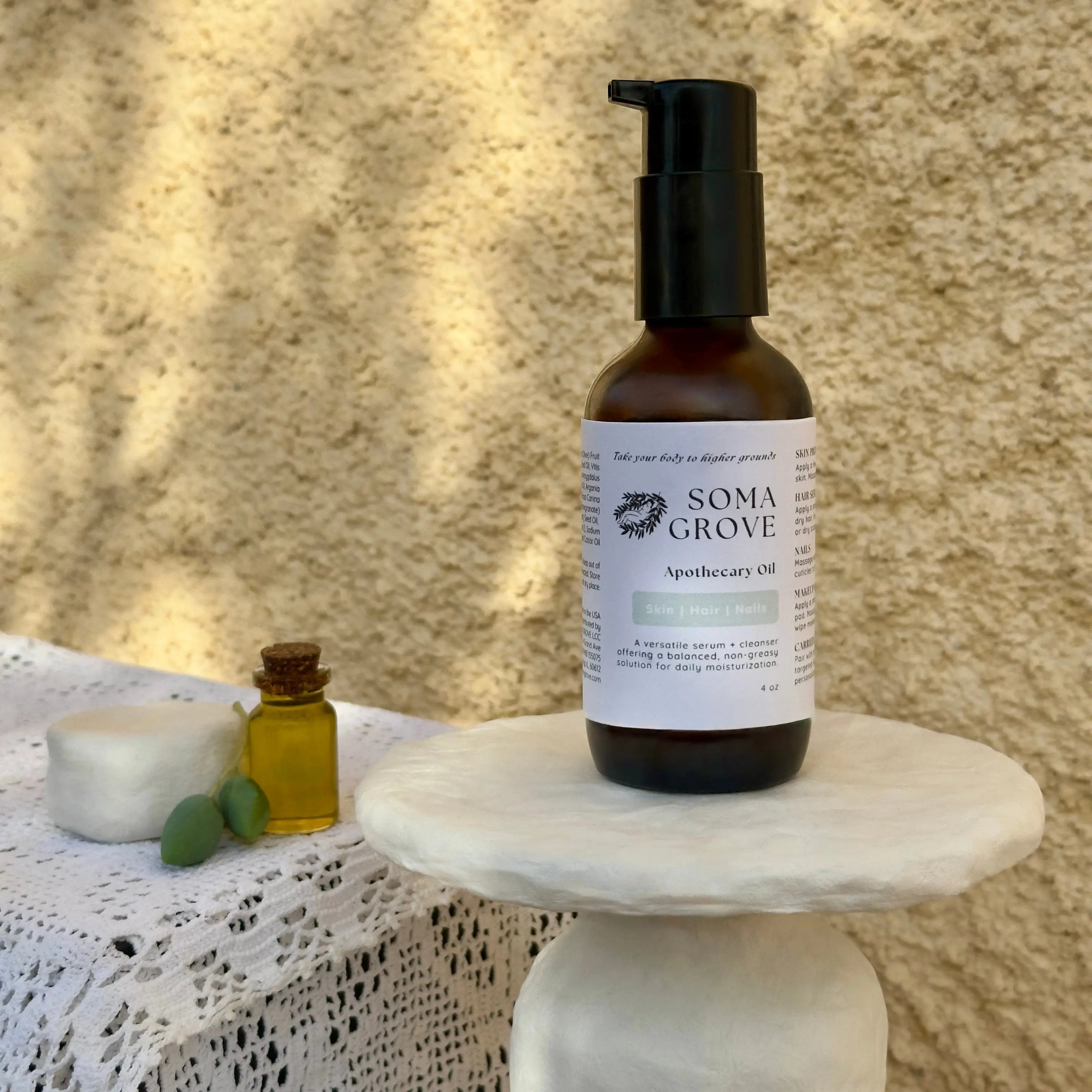 Soma Grove Apothecary Oil bottle on a marble stand with a textured beige background.